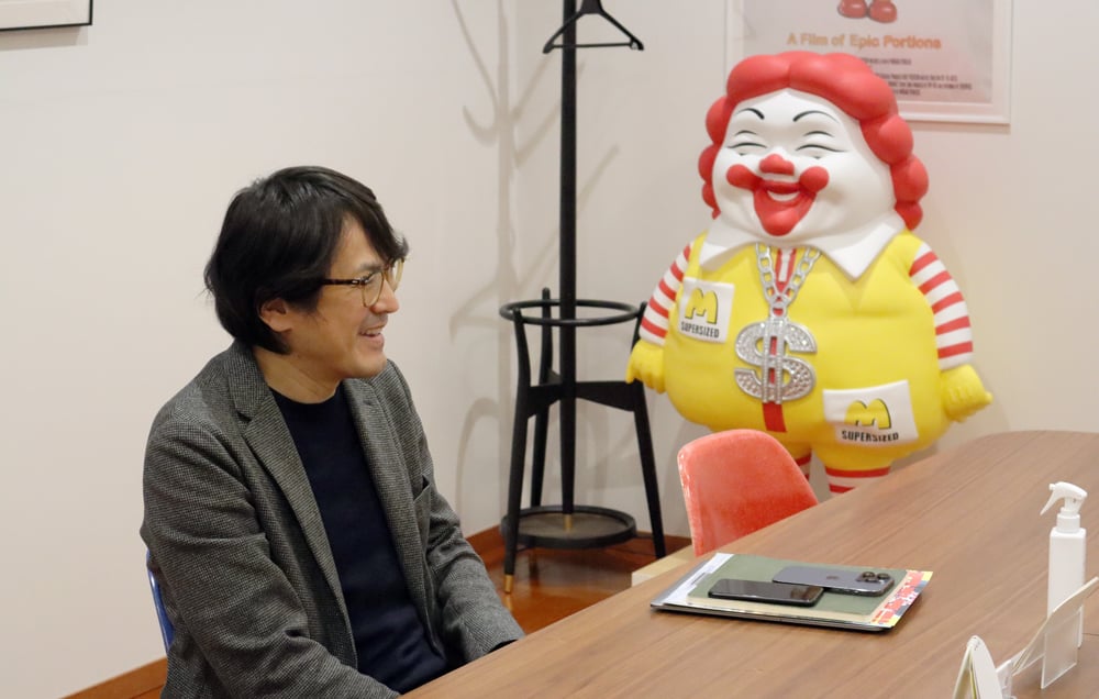 カテル有限会社笠倉規克様がオフィス内でインタビューに応じる様子。背後には遊び心が感じられるオブジェが置かれている